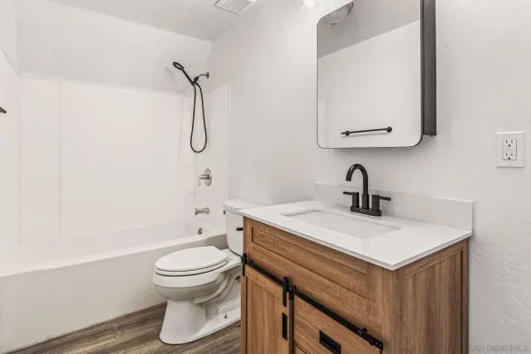 a bathroom with a granite countertop sink toilet a mirror and shower