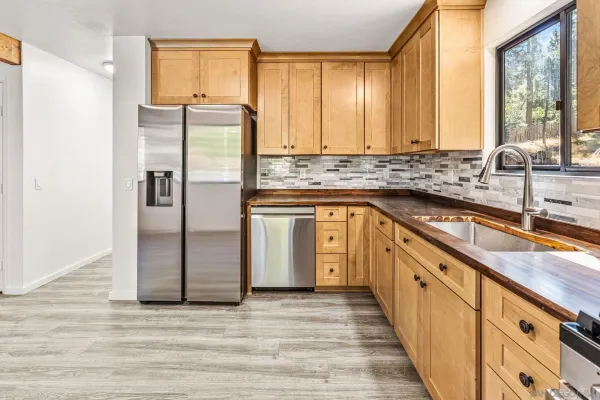 a kitchen with stainless steel appliances granite countertop a refrigerator a sink and white cabinets