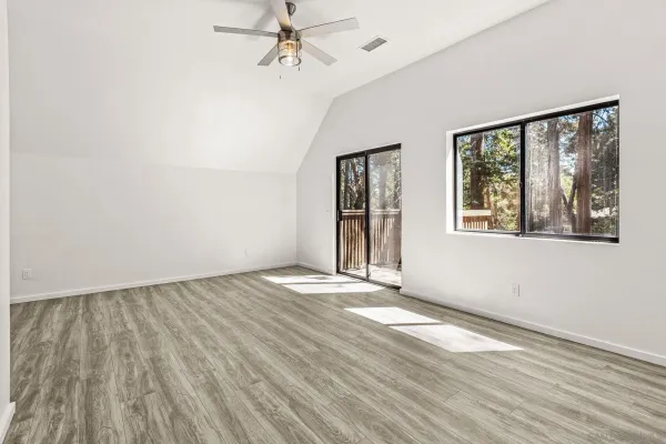 a view of an empty room with a window and wooden floor