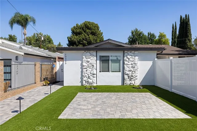 a front view of a house with a yard and potted plants