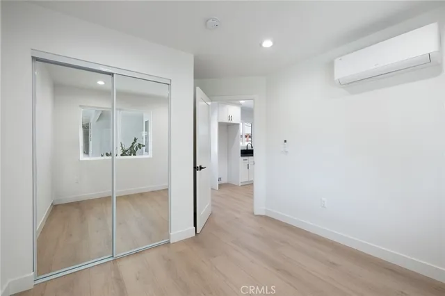 a view of a hallway with wooden floor and a bathroom