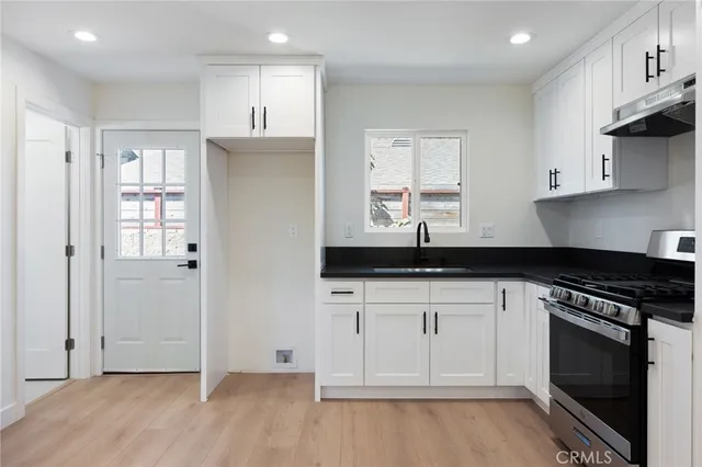 a kitchen with granite countertop a sink cabinets and stainless steel appliances