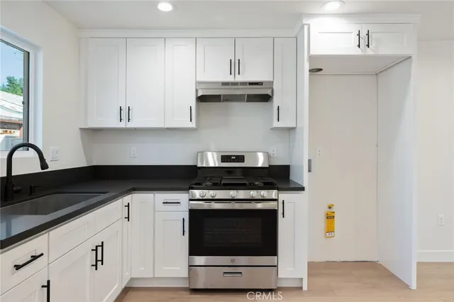 a kitchen with stainless steel appliances granite countertop a stove a sink and a microwave