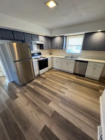 a view of an empty room and a kitchen