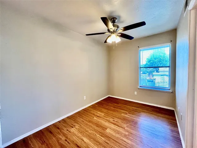 a view of empty room with wooden floor and fan