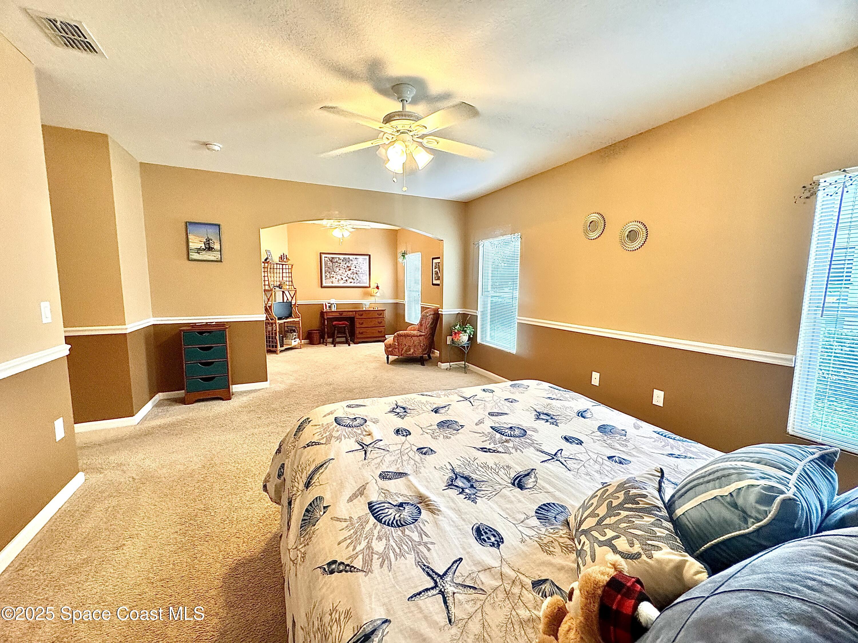 217 Briarcliff Circle Sebastian, FL 32958 - Photo 25 of 36 a bedroom with a large bed and a chandelier