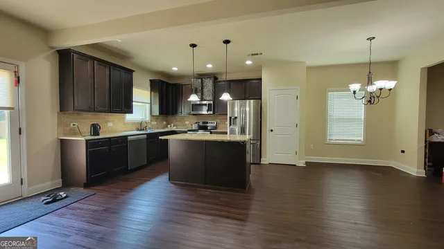 a kitchen with stainless steel appliances kitchen island granite countertop wooden floors and a view of living room