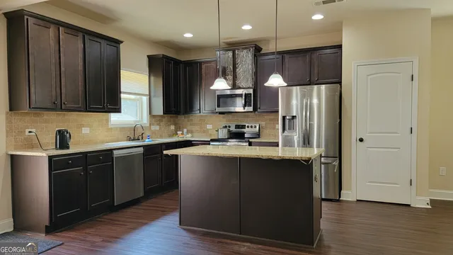 a kitchen with kitchen island granite countertop wooden cabinets and a refrigerator