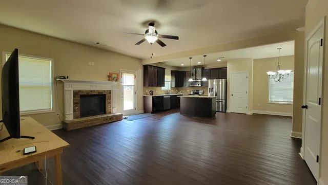 a view of a kitchen with a stove a microwave oven a fireplace wooden floor and a kitchen
