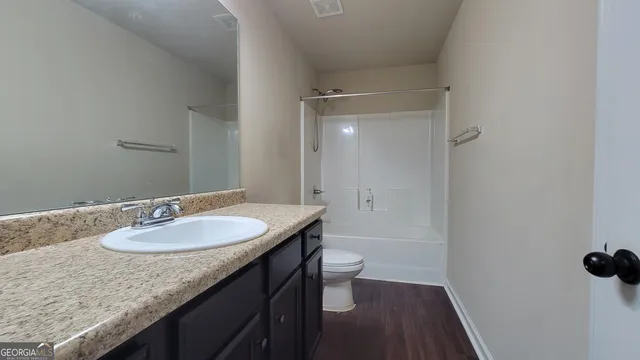 a bathroom with a granite countertop sink a mirror and a toilet