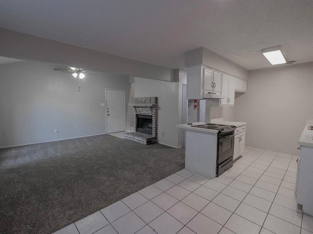 675 Harbor Drive North, Unit D Azle, TX 76020 - Photo 2 of 8 Kitchen with white cabinets, a ceiling fan, light countertops, black range with electric cooktop, and a fireplace