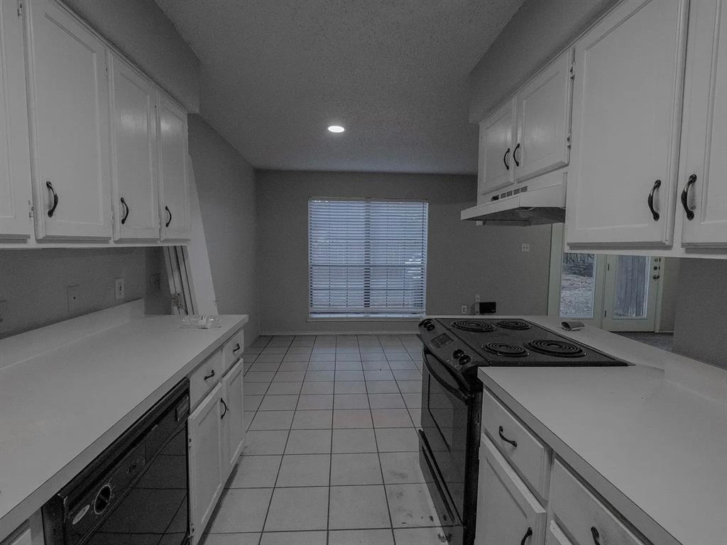 675 Harbor Drive North, Unit D Azle, TX 76020 - Photo 5 of 8 Kitchen with white cabinets, black appliances, light countertops, light tile patterned flooring, and a textured ceiling