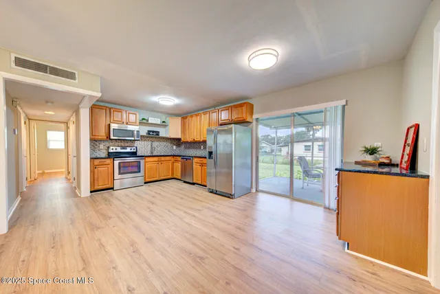 a large kitchen with stainless steel appliances granite countertop a refrigerator and a stove top oven