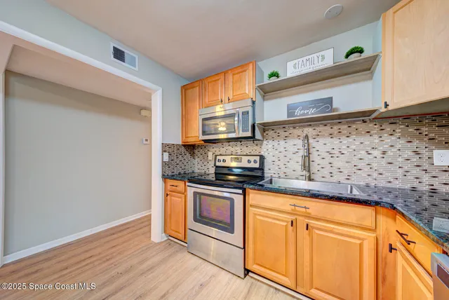 a kitchen with stainless steel appliances granite countertop a stove a sink and a microwave
