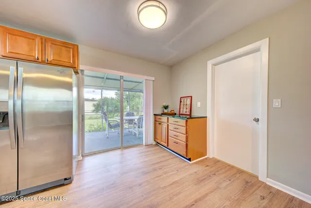 a view of a kitchen with a fridge and wooden floor