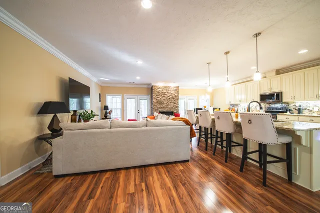 a living room with couches chairs and kitchen view with wooden floor