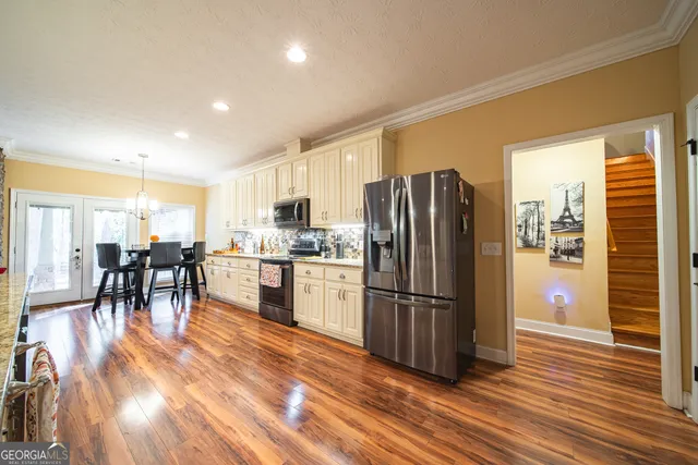 a kitchen with granite countertop a refrigerator a stove a sink a dining table and chairs with wooden floor