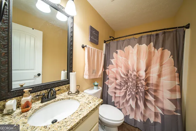 a bathroom with a granite countertop sink toilet and shower