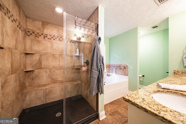 a bathroom with a granite countertop sink a toilet and shower