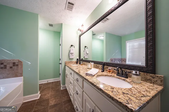a bathroom with a granite countertop double vanity sink and a mirror