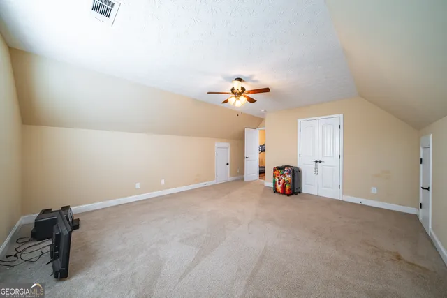 an empty room with a chandelier fan and windows