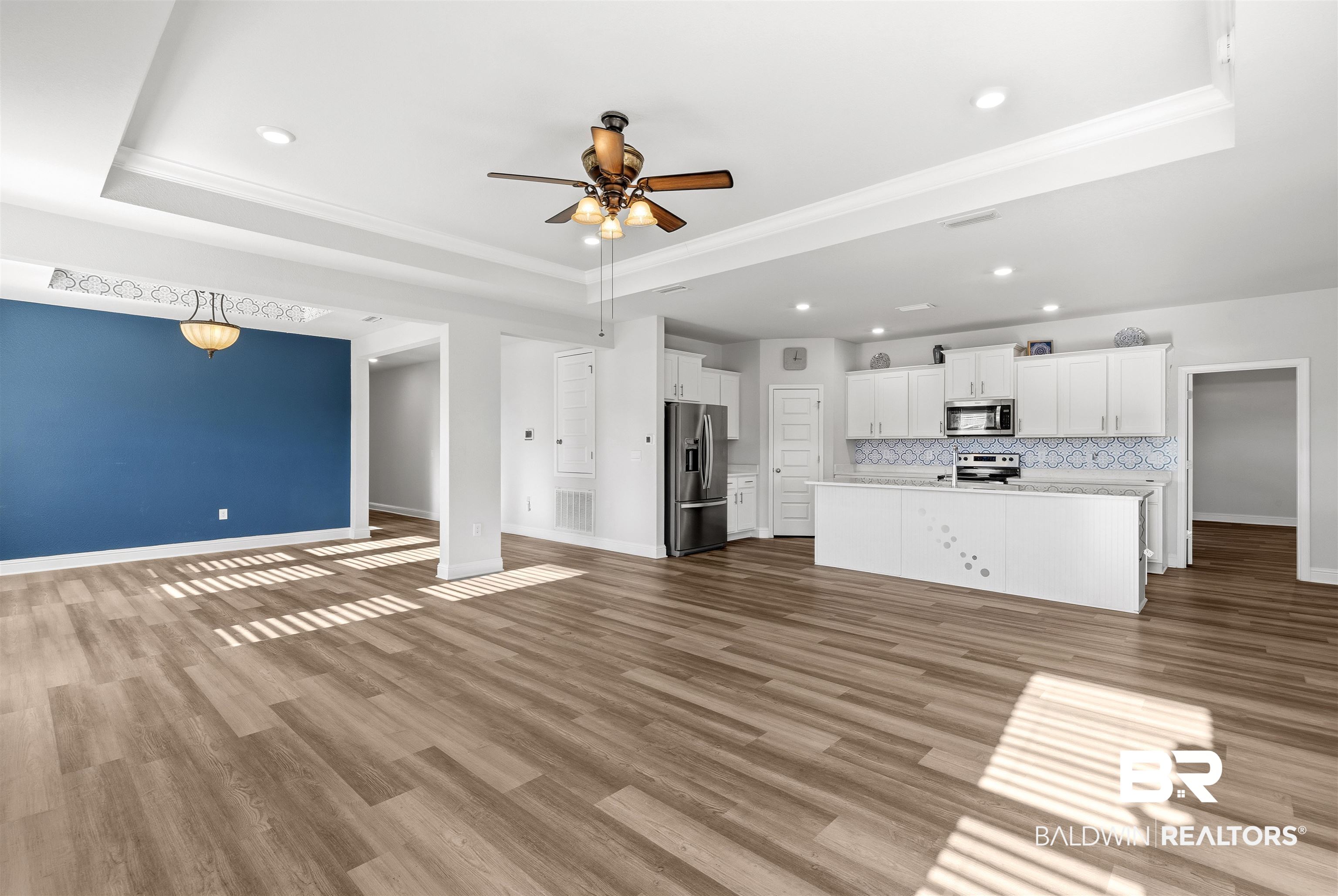 485 Shepard Street Gulf Shores, AL 36542 - Photo 10 of 53 Unfurnished living room featuring ceiling fan, light wood-style flooring, a tray ceiling, crown molding, and recessed lighting