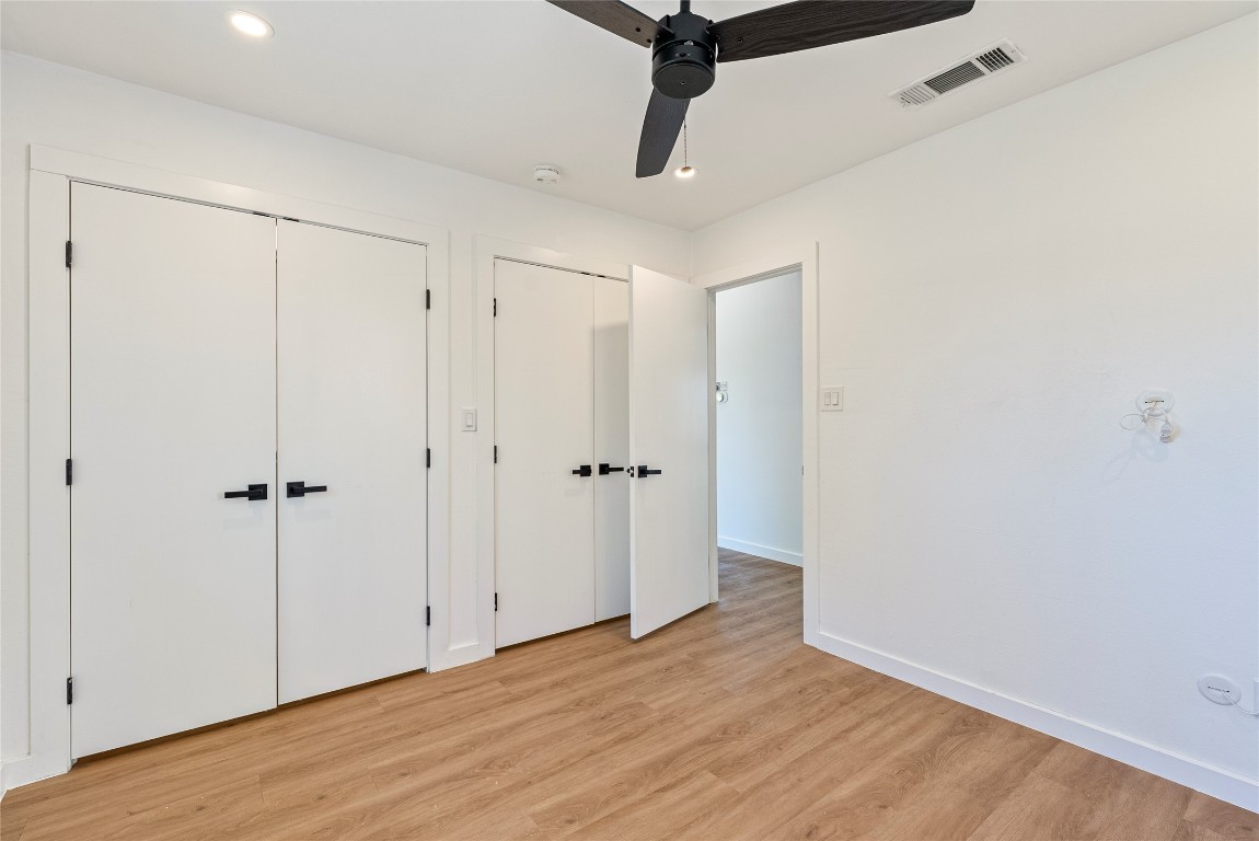 5200 King Charles Drive Austin, TX 78724 - Photo 12 of 22 Unfurnished bedroom with multiple closets, wood finished floors, a ceiling fan, and recessed lighting
