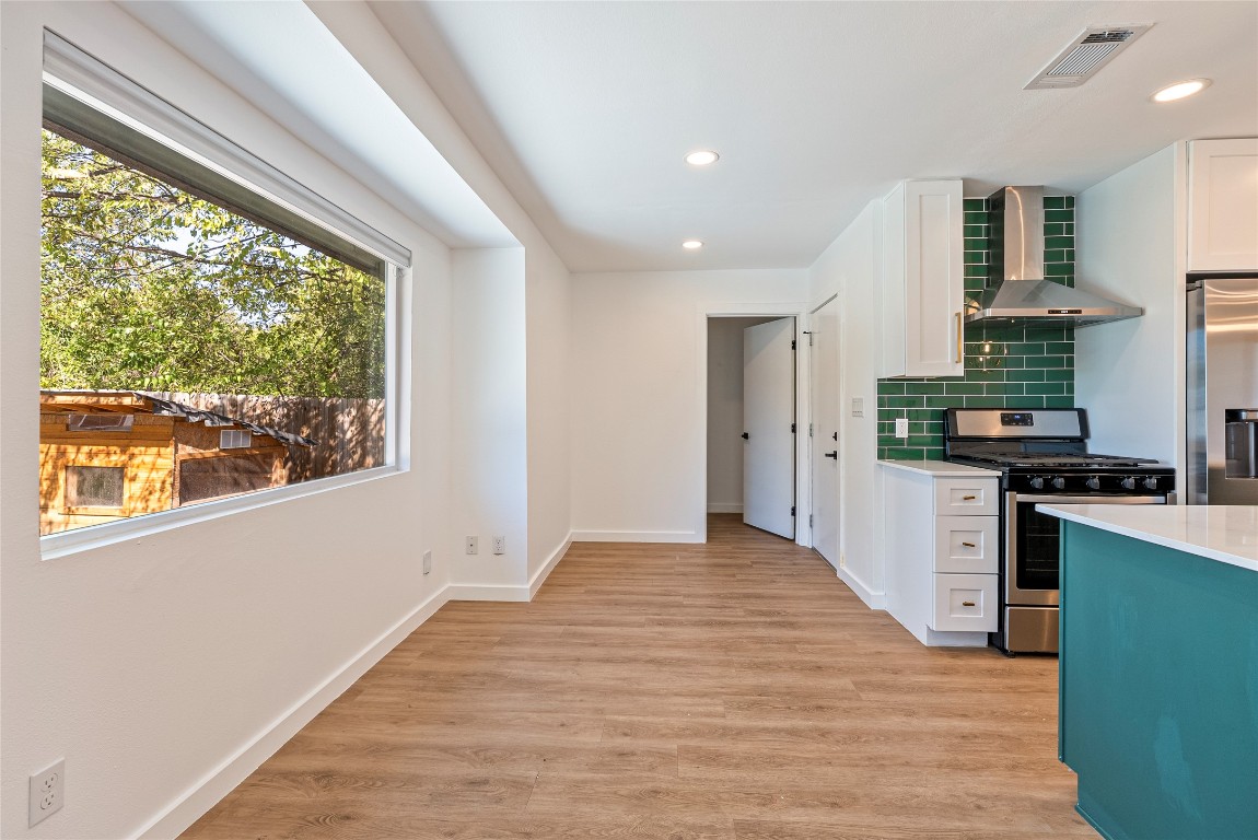5200 King Charles Drive Austin, TX 78724 - Photo 9 of 22 Kitchen featuring decorative backsplash, stainless steel appliances, wall chimney exhaust hood, white cabinets, and recessed lighting