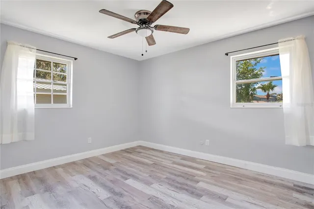 a view of an empty room with a window and a ceiling fan