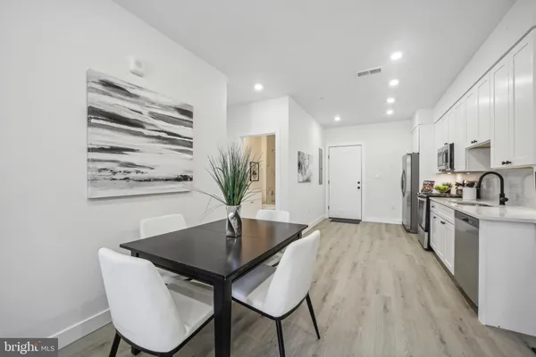 a kitchen with stainless steel appliances granite countertop a kitchen island a stove a sink a dining table and chairs