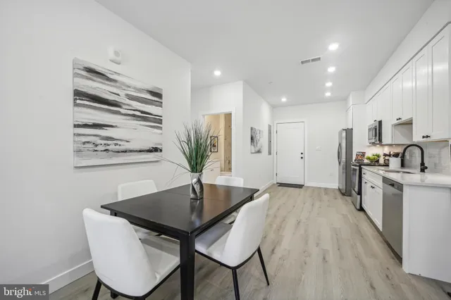 a kitchen with stainless steel appliances granite countertop a kitchen island a stove a sink a dining table and chairs