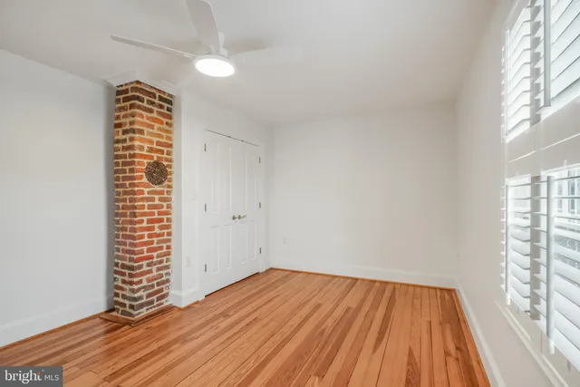 an empty room with wooden floor chandelier fan and windows
