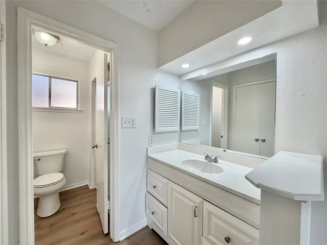 a spacious bathroom with a granite countertop sink a toilet and a mirror