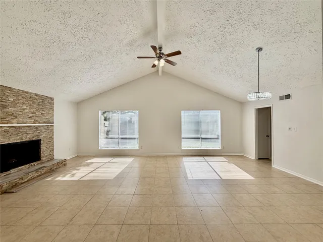 an empty room with windows and fireplace