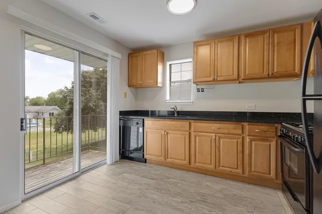 a kitchen with stainless steel appliances granite countertop a refrigerator a sink and dishwasher with a large window