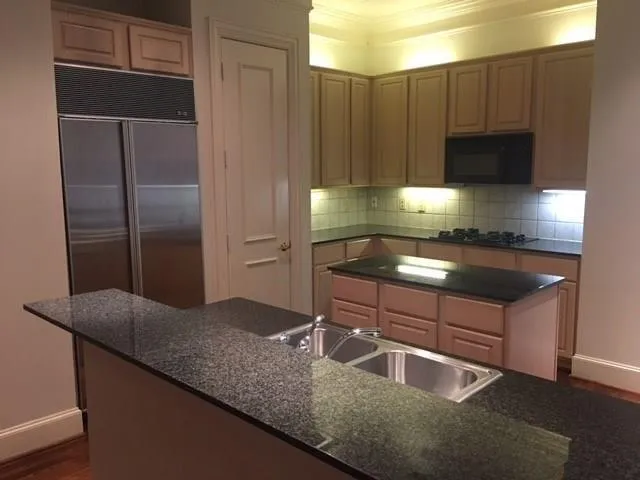 a kitchen with kitchen island granite countertop a sink refrigerator and microwave