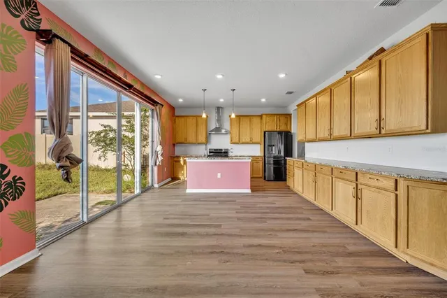 a view of kitchen with kitchen island wooden floor center island and stainless steel appliances
