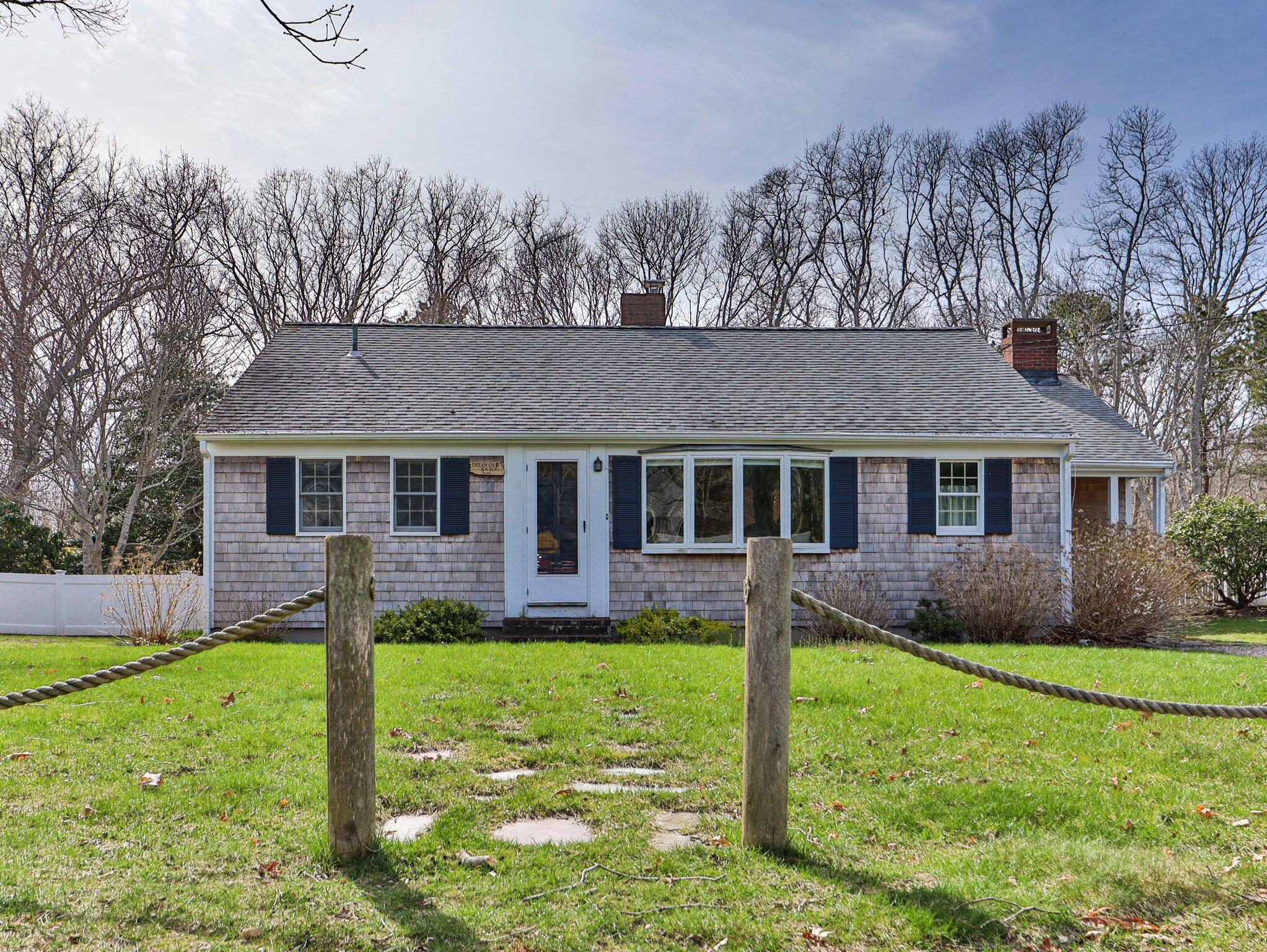 a front view of a house with a yard and a large tree