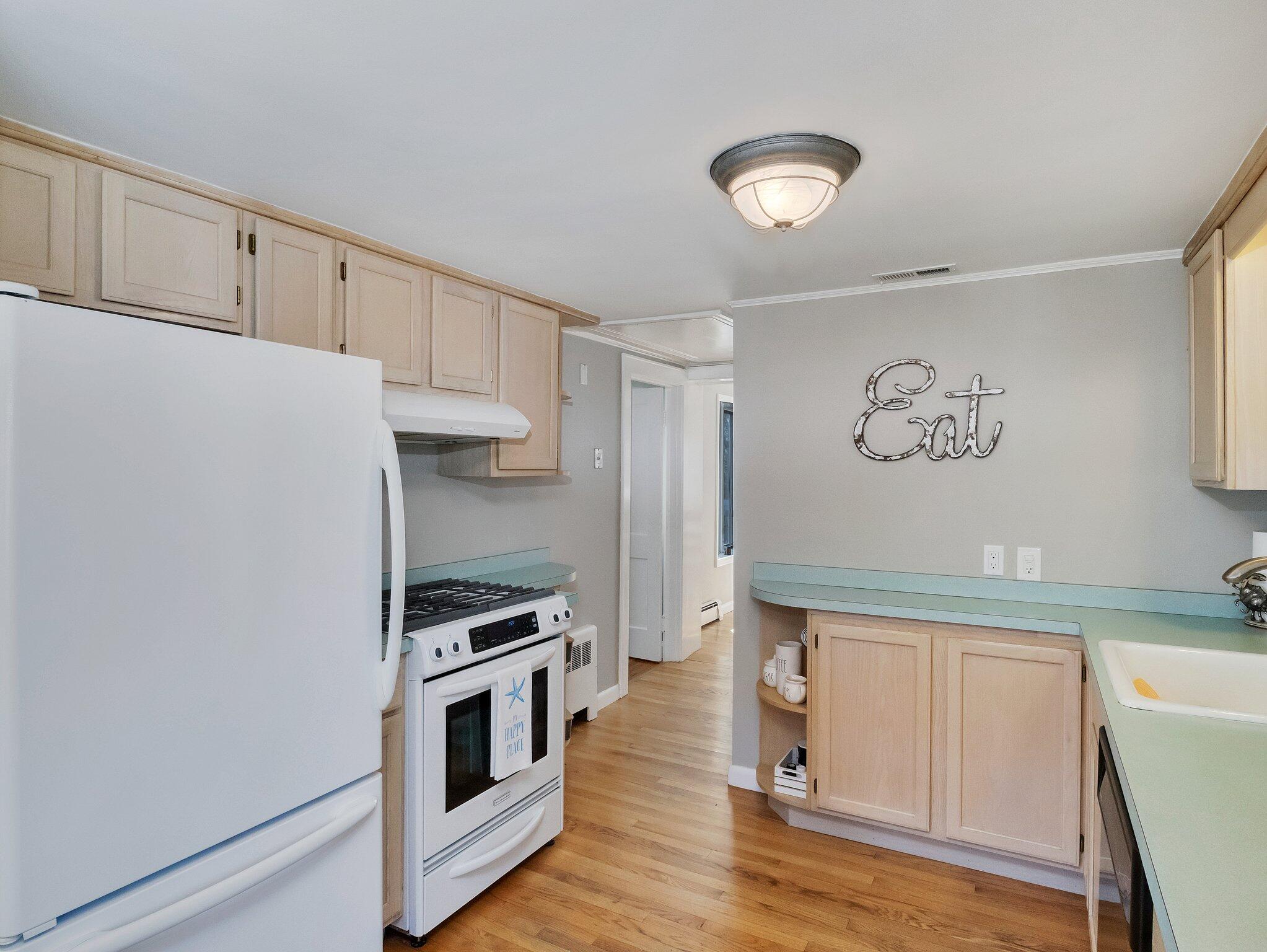 41 Harbor Road West Yarmouth, MA 02673 - Photo 16 of 56 a kitchen with granite countertop a refrigerator a stove and white cabinets with wooden floor