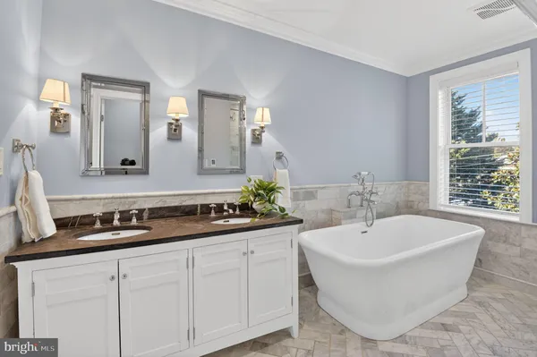 a bathroom with a bathtub a double vanity sink and mirror