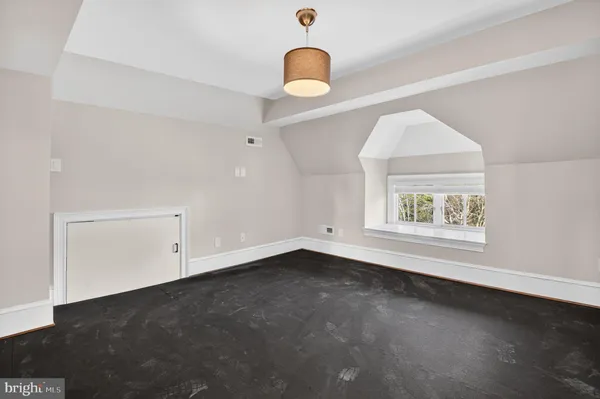 a view of an empty room with wooden floor and window