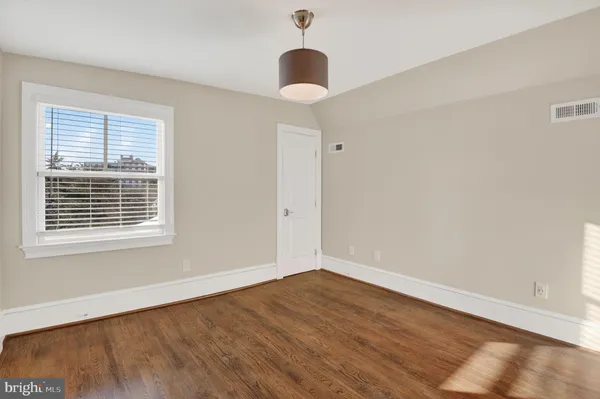 a view of empty room with wooden floor and window