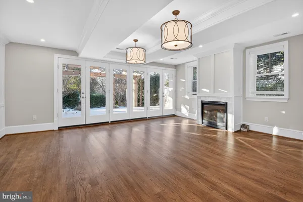 an empty room with wooden floor fireplace and windows
