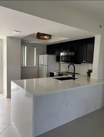 a living room with stainless steel appliances kitchen island granite countertop a sink and a granite counter tops