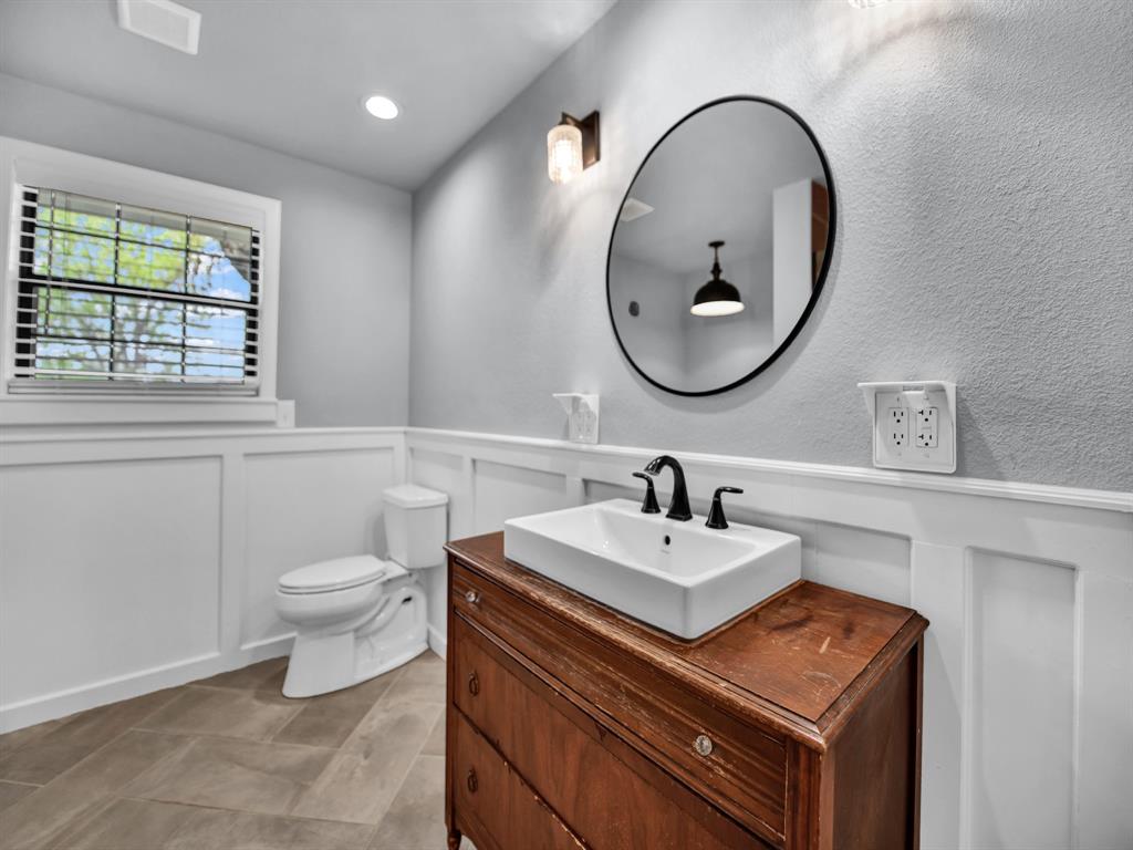 305 Gandy Street Lipan, TX 76462 - Photo 21 of 40 a bathroom with a toilet a sink a mirror and a window