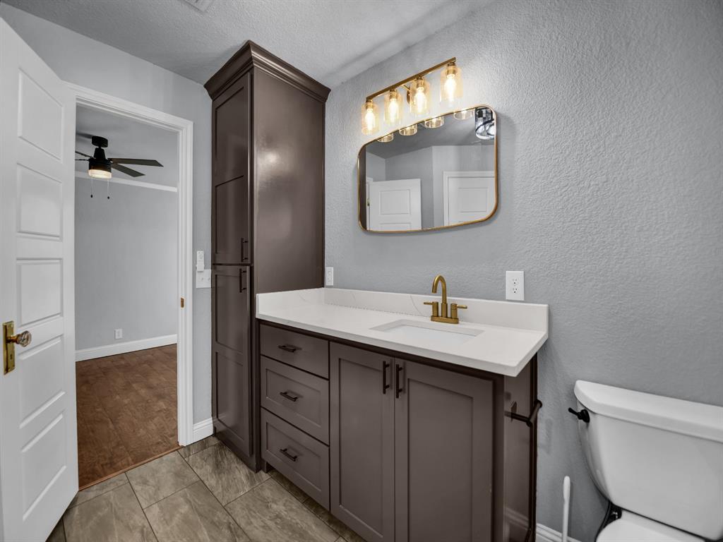 305 Gandy Street Lipan, TX 76462 - Photo 23 of 40 a bathroom with a granite countertop sink a mirror and a toilet