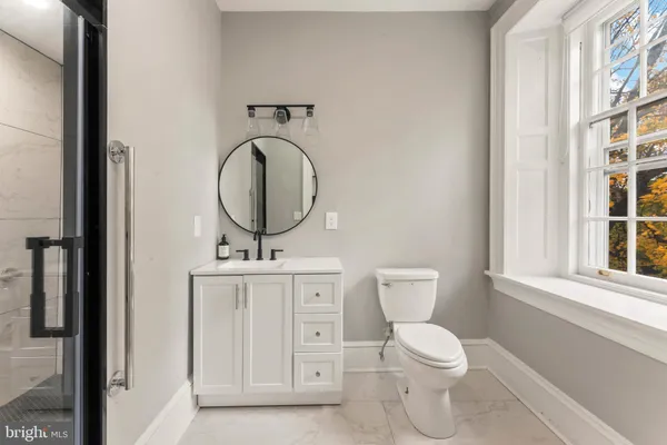 a bathroom with a toilet a sink a mirror and vanity