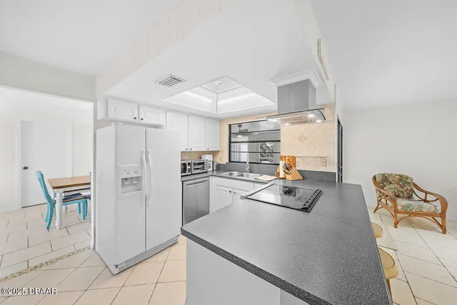 a kitchen with a refrigerator a stove a sink dishwasher and white cabinets with wooden floor