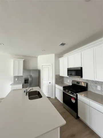 a kitchen with kitchen island a sink a stove and refrigerator