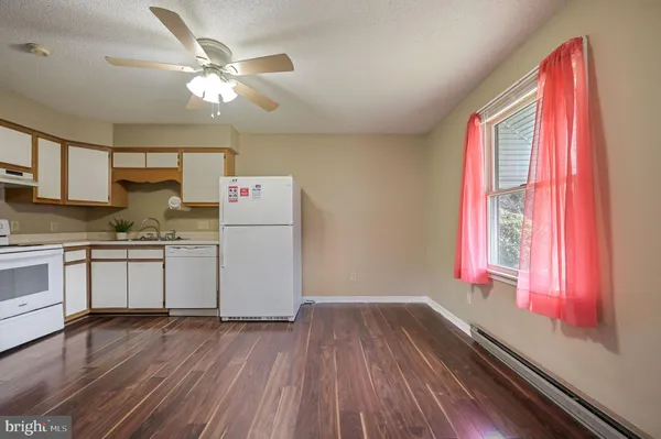 a kitchen with a refrigerator a stove top oven a sink and wooden floor